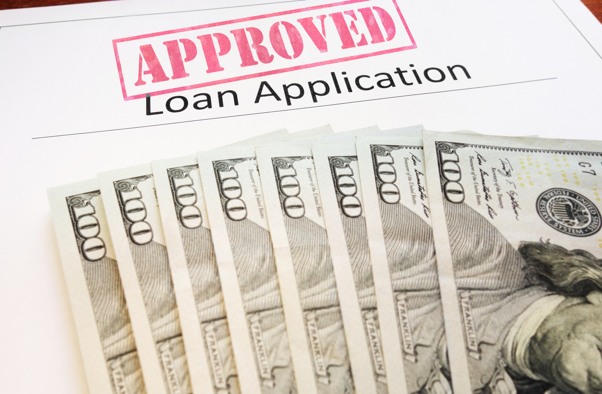Approved Loan Application Paperwork with DOllar Bills